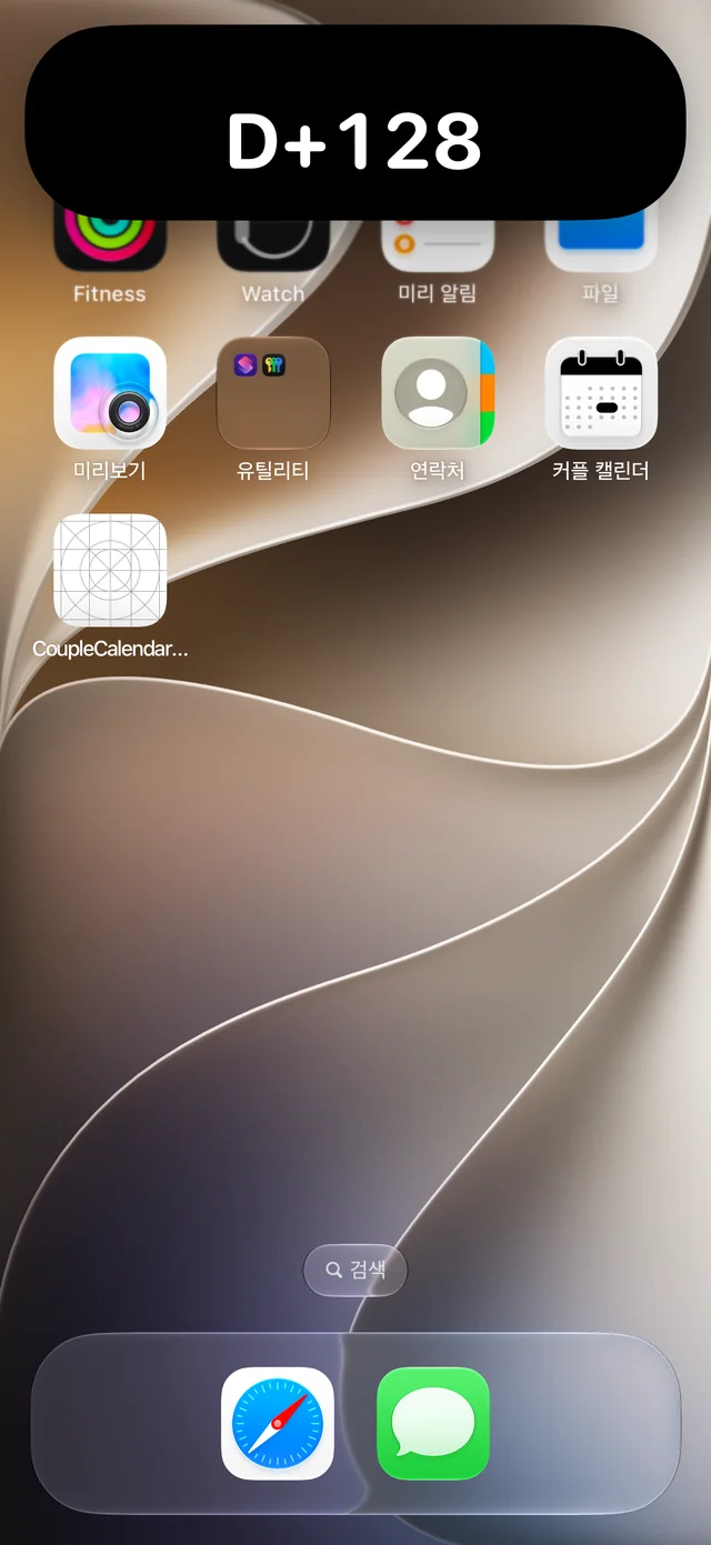 다이나믹 아일랜드를 길게 눌러 펼친 D+128 카드가 보이는 iPhone 홈 화면