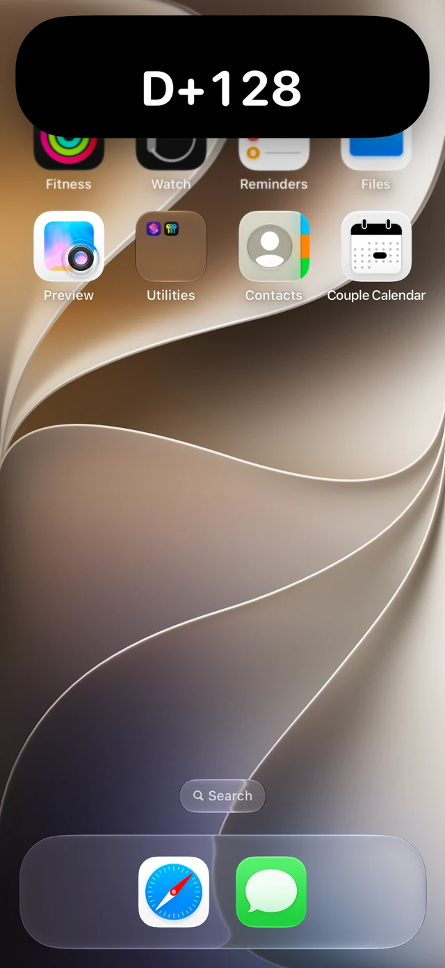 iPhone Home Screen with the D+128 card expanded by touching and holding Dynamic Island